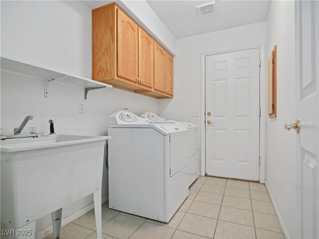 clothes washing area with light tile patterned flooring, cabinets, sink, and washing machine and dryer