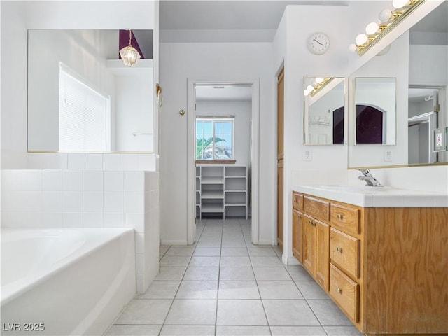 bathroom with tile patterned floors, a washtub, and vanity