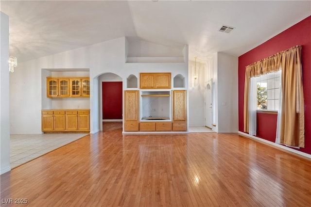 unfurnished living room featuring a chandelier, light hardwood / wood-style floors, and vaulted ceiling