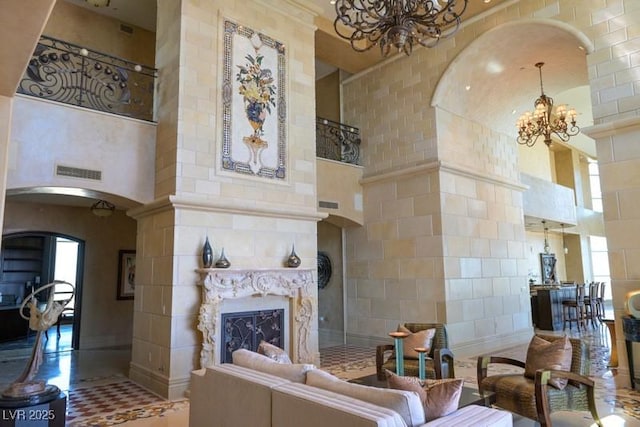 living room featuring a premium fireplace, a high ceiling, and a chandelier