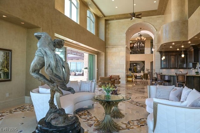 interior space featuring a towering ceiling and ceiling fan with notable chandelier