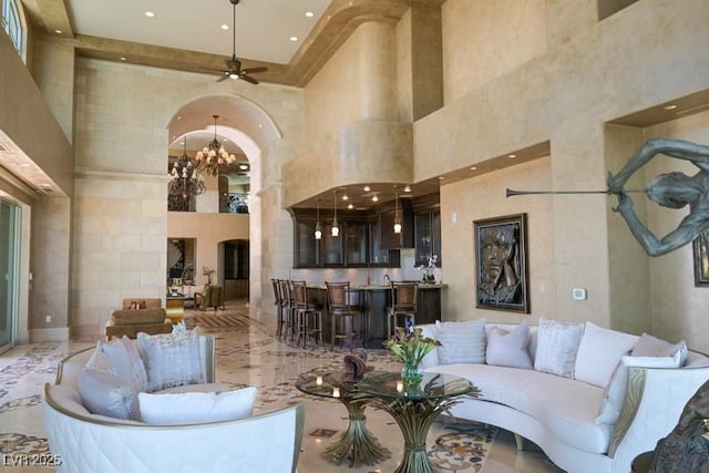 living room with ceiling fan with notable chandelier and a high ceiling