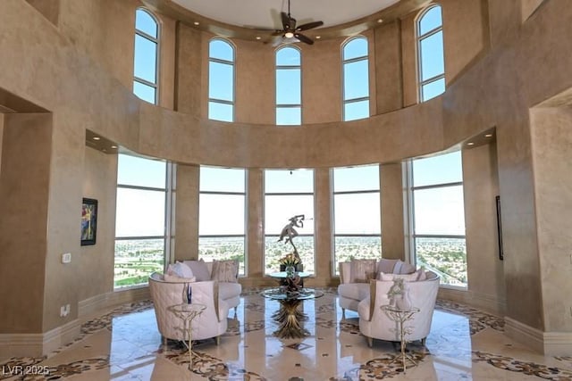 living room featuring a towering ceiling, plenty of natural light, and ceiling fan