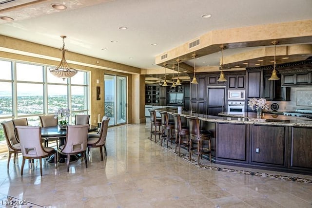 kitchen featuring light stone countertops, dark brown cabinetry, oven, and built in microwave