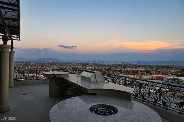 patio terrace at dusk with grilling area, a mountain view, and area for grilling