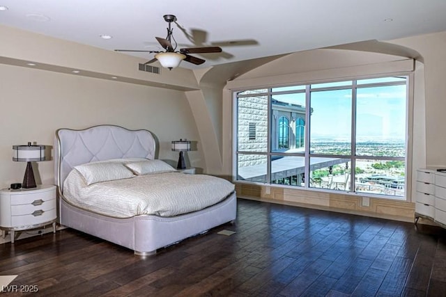 bedroom with ceiling fan, dark wood-type flooring, and multiple windows