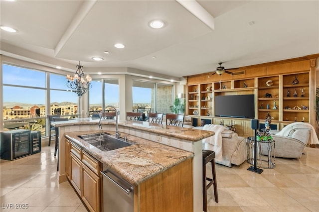 kitchen with decorative light fixtures, an island with sink, sink, a breakfast bar area, and light stone counters