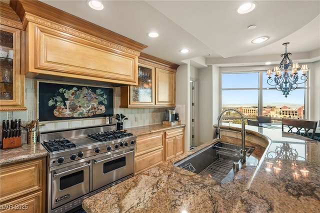 kitchen featuring sink, decorative backsplash, range with two ovens, hanging light fixtures, and light stone counters