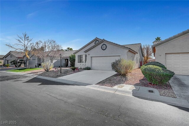 view of front of house with stucco siding, concrete driveway, an attached garage, and a tiled roof