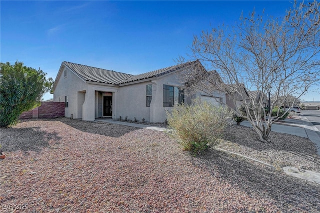 back of house with stucco siding, a tiled roof, and fence