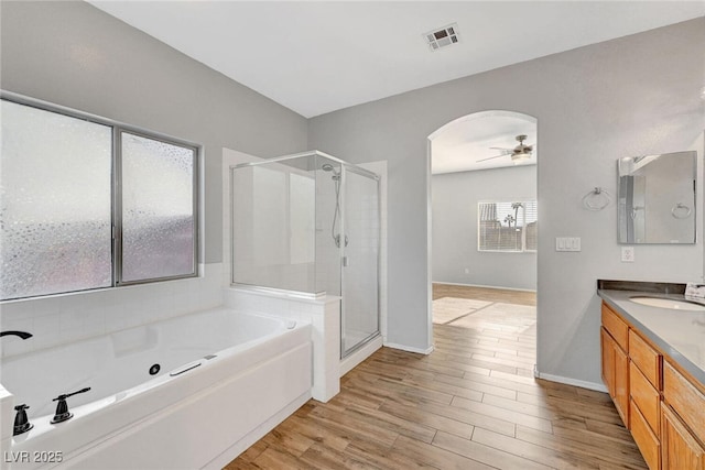 full bath with a whirlpool tub, wood finished floors, a shower stall, ceiling fan, and vanity