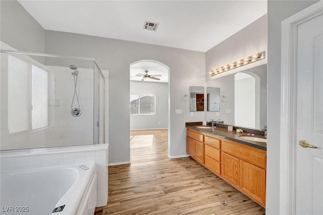 full bathroom with wood finished floors, visible vents, ceiling fan, a sink, and a shower stall