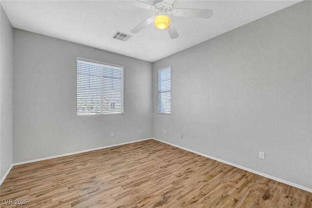 unfurnished room featuring baseboards, wood finished floors, visible vents, and ceiling fan