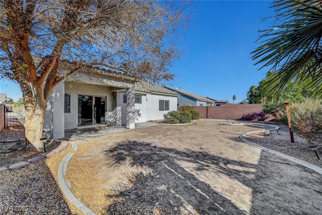 back of property featuring a tiled roof, fence, and stucco siding