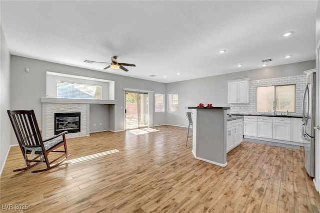 kitchen featuring dark countertops, light wood finished floors, white cabinetry, and ceiling fan