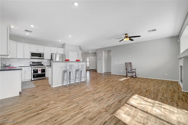 kitchen featuring open floor plan, tasteful backsplash, visible vents, and appliances with stainless steel finishes