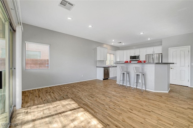 5919 Pavilion Lakes Ave, Las Vegas, NV 89122 - kitchen featuring appliances with stainless steel finishes, white cabinetry, light wood-style floors, decorative backsplash, and a kitchen island