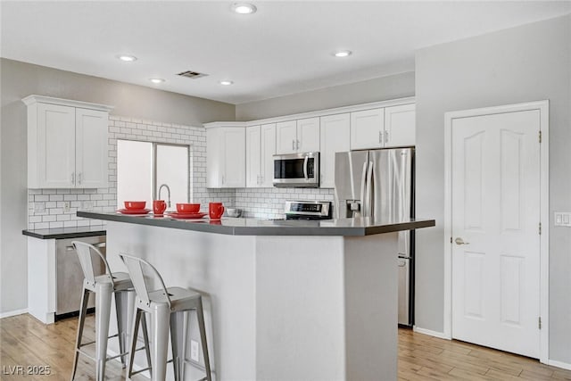 kitchen featuring visible vents, appliances with stainless steel finishes, light wood-style flooring, and white cabinets