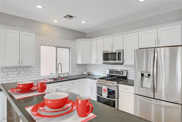 5919 Pavilion Lakes Ave, Las Vegas, NV 89122 - kitchen featuring appliances with stainless steel finishes, backsplash, white cabinets, dark countertops, and recessed lighting
