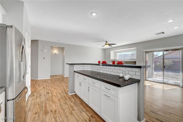 kitchen with visible vents, ceiling fan, light wood-style floors, dark countertops, and stainless steel fridge