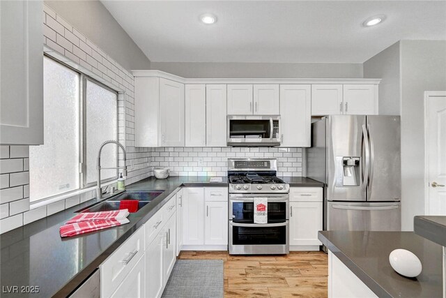 5919 Pavilion Lakes Ave, Las Vegas, NV 89122 - kitchen with appliances with stainless steel finishes, dark countertops, white cabinetry, light wood-type flooring, and recessed lighting
