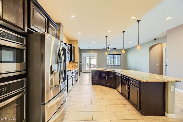 kitchen featuring ceiling fan, sink, hanging light fixtures, a kitchen island with sink, and appliances with stainless steel finishes