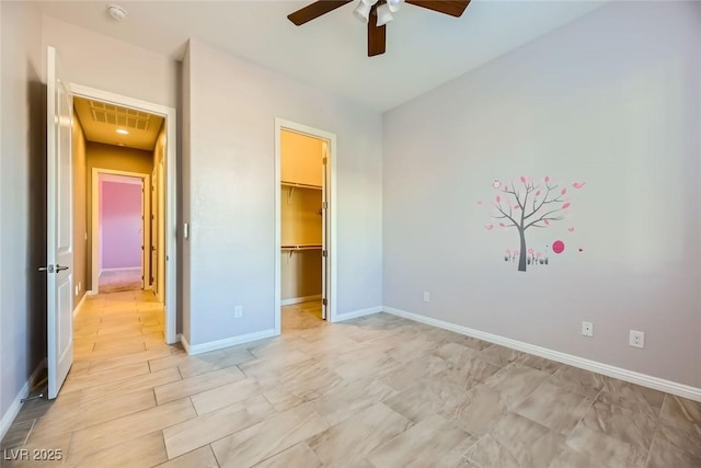 unfurnished bedroom featuring ceiling fan, a closet, and a spacious closet