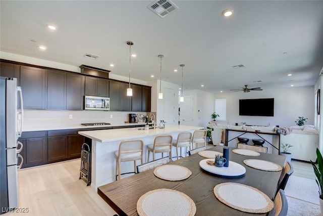 dining area featuring ceiling fan, sink, and light hardwood / wood-style flooring