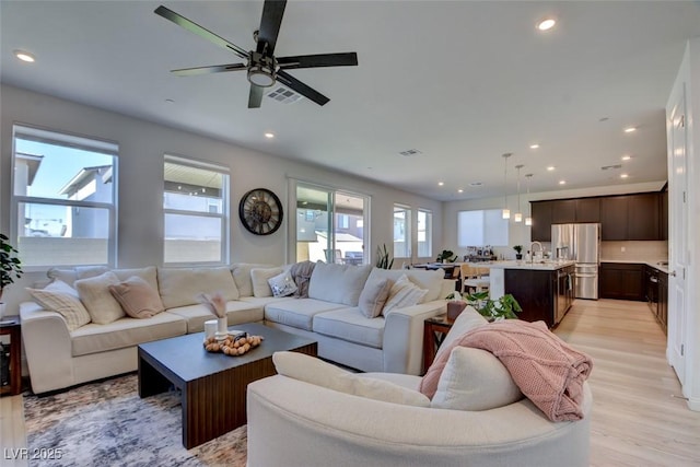 living room with light wood-type flooring, ceiling fan, a healthy amount of sunlight, and sink