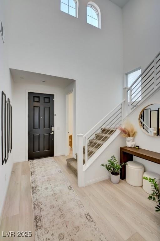 entrance foyer with light hardwood / wood-style floors and a towering ceiling