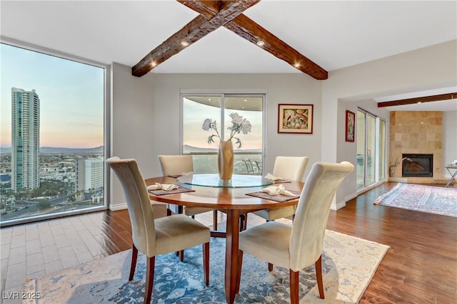 dining room featuring a fireplace, expansive windows, and beamed ceiling