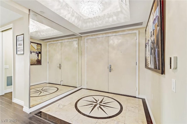 foyer featuring a tray ceiling, hardwood / wood-style flooring, and an inviting chandelier