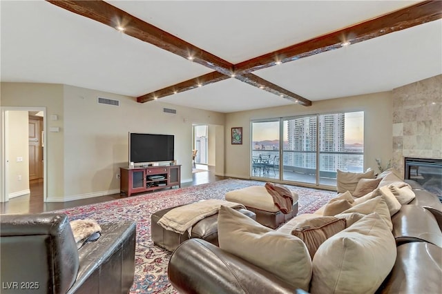 living room featuring beam ceiling and a tile fireplace