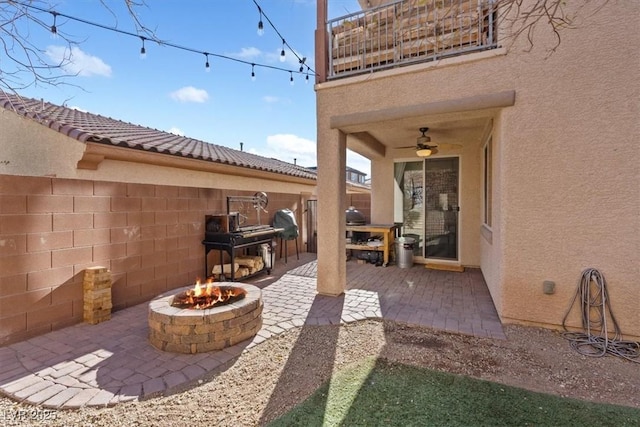 view of patio with a fire pit, ceiling fan, and a balcony