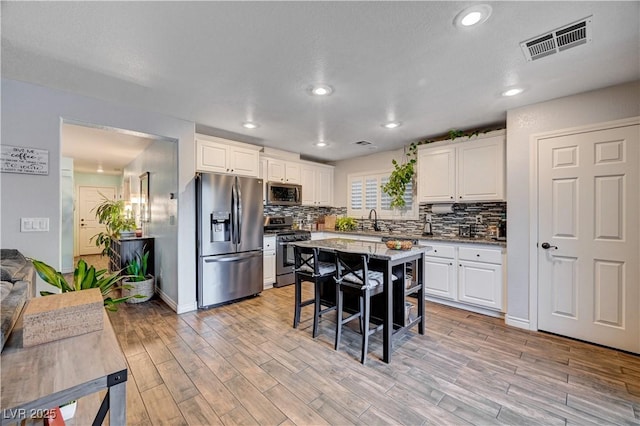 kitchen with a kitchen breakfast bar, white cabinetry, a kitchen island, and stainless steel appliances