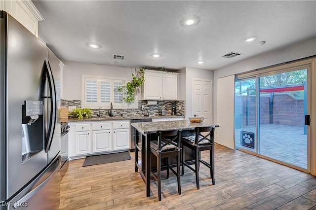 kitchen featuring a breakfast bar area, white cabinetry, a center island, and appliances with stainless steel finishes