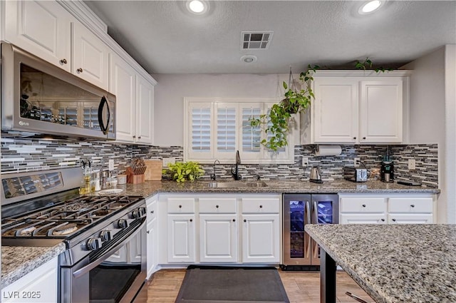 kitchen with white cabinets, stainless steel appliances, and beverage cooler