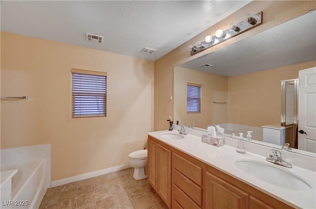 bathroom with a textured ceiling, vanity, toilet, and a bathing tub