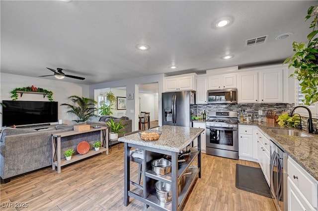 kitchen featuring light stone counters, stainless steel appliances, white cabinetry, and sink