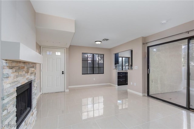 unfurnished living room featuring light tile patterned floors and a stone fireplace