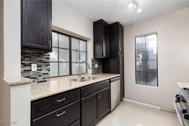 kitchen featuring light stone countertops, sink, stainless steel appliances, backsplash, and light tile patterned floors