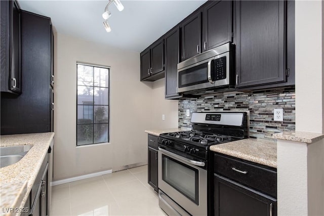 kitchen with decorative backsplash, light stone counters, light tile patterned floors, and stainless steel appliances