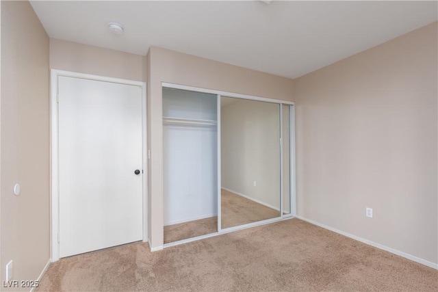 unfurnished bedroom with light carpet and a closet