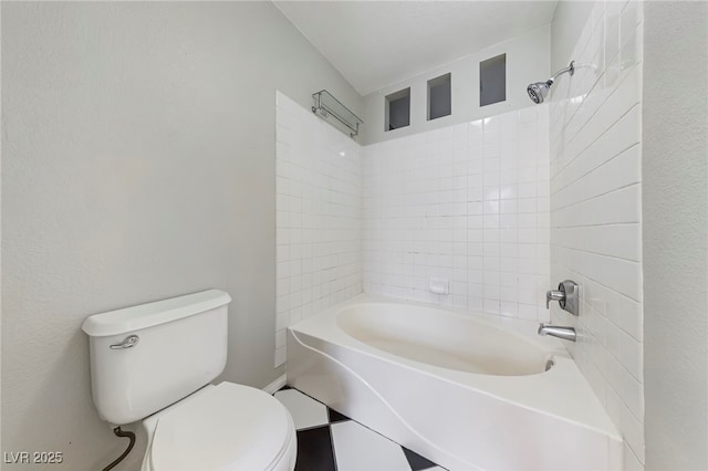 bathroom featuring toilet and tiled shower / bath