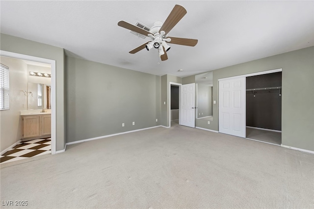 unfurnished bedroom with ensuite bathroom, a closet, light colored carpet, and ceiling fan