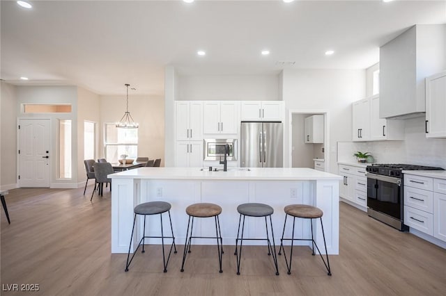 kitchen with a kitchen island with sink, white cabinets, and appliances with stainless steel finishes