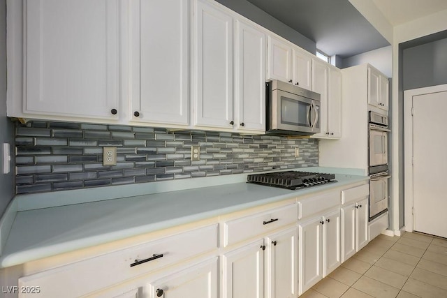 kitchen featuring decorative backsplash, light tile patterned floors, stainless steel appliances, and white cabinetry