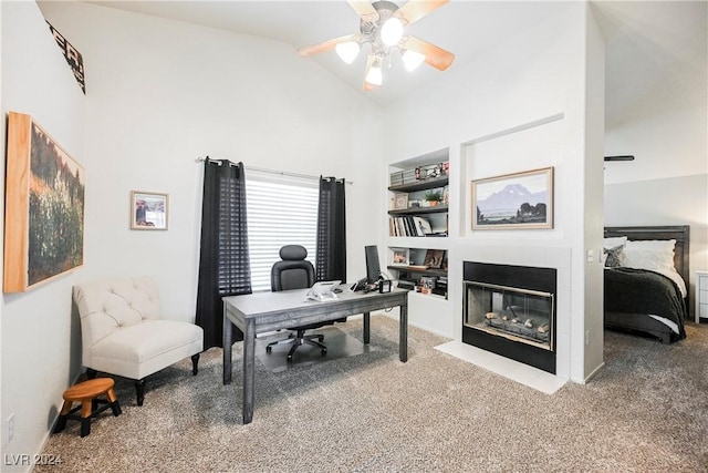 carpeted home office with vaulted ceiling, ceiling fan, and built in shelves