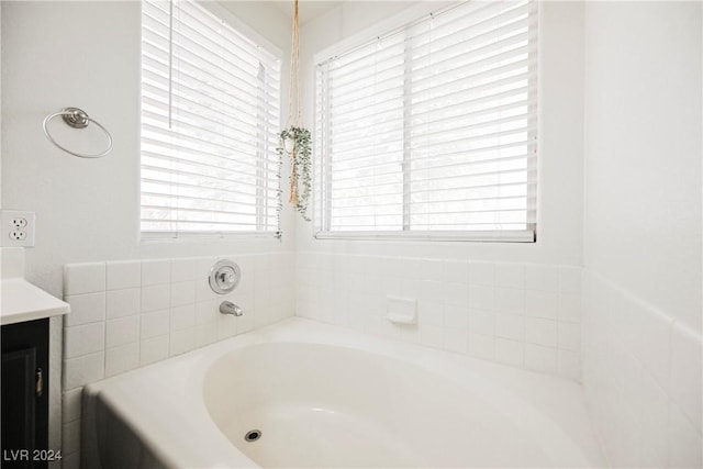 bathroom with plenty of natural light, a washtub, and vanity