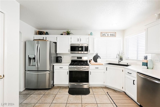 kitchen with sink, white cabinets, light tile patterned flooring, and appliances with stainless steel finishes